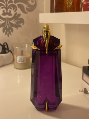 Alien parfym 90ml Thierry Mugler - Alien från Mugler är en ikonisk parfym i en lila, multifacetterad glasflaska med gulddetaljer. Flaskan har en futuristisk, ädelstensliknande form och rymmer 90 ml eau de parfum. Doften är djup och unik. Pris kan diskuteras 💓