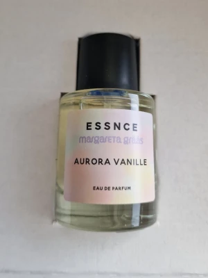Aurora Vanille parfym från ESSNCE - Aurora Vanille från ESSNCE är en Eau de Parfum med en stilren, genomskinlig glasflaska och svart kork. Etiketten har en mjuk pastellton och flaskan har en modern, minimalistisk design. Doften är framtagen av Margareta Grääs och har en tydlig vaniljkaraktär. Endast testad