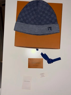 L,V - ✨ Diskret lyx. Maximal känsla. ✨  Den här mössan är definitionen av sofistikerad coolness 🖤 Ett elegant, vävt mönster som fångar ljuset precis lagom, kombinerat med en mjuk och följsam kvalitet som sitter perfekt på huvudet. Den nedvikta kanten ger en stilren silhuett som skriker klass – utan att behöva höja rösten.  Perfekt för dig som vill utstråla självsäker elegans, oavsett om du bär ullrock i stan 🏙️ eller en avslappnad jacka.