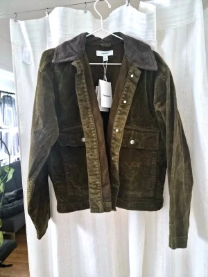 Olivgrön manchesterjacka från Topshop - Säljer en olivgrön manchesterjacka från Topshop med kontrastkrage i mörkare brun ton. Oanvänd med lapparna kvar. Storlek S. Inköpspris: 1399:-                                                                 