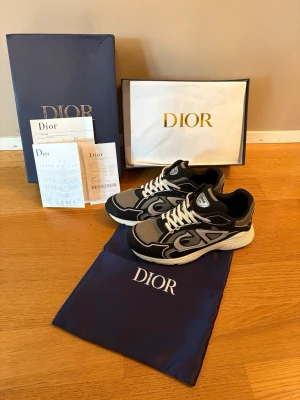 Dior b30 sneakers  - Snygga svart gröna Dior b30 sneakers med vita och grå detaljer samt tydligt CD-logo på sidan. Skorna har en chunky vit sula och vita skosnören. Tillverkade i en mix av mesh och mocka för en modern look. Perfekta för dig som vill sticka ut med exklusiva sneakers.