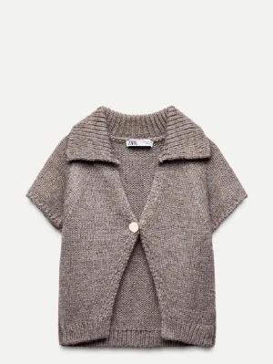 Beige stickad väst med krage - Stickad beige väst från Zara med kort ärm, bred krage och en knapp framtill. Perfekt att slänga över en t-shirt eller skjorta för en chill och trendig look. Mjuk och skön känsla tack vare det stickade materialet.