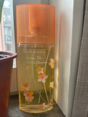 Elizabeth Arden Green Tea Nectarine Blossom - Fräsch parfym från Elizabeth Arden, Green Tea Nectarine Blossom. Flaskan är transparent med blommigt mönster och har en orange plastkork. Doften är inspirerad av grönt te och nektarinblom, perfekt för dig som gillar fruktiga och blommiga toner.