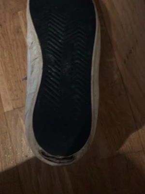 Vita phillipe model skor met svarta blå detaljer -  vita phillipe model  sneakers med svarta och blå detaljer på hälen och svart sula. Skorna har lågt skaft, vita snören och är tillverkade i canvas med gummisula. Perfekta för en avslappnad och stilren look.