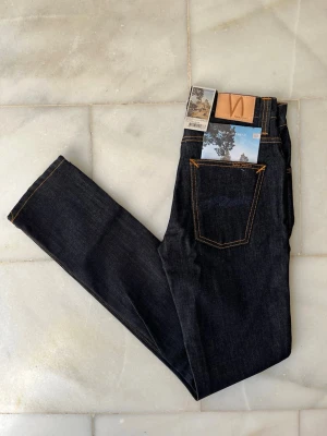 Mörkblå jeans från Nudie Jeans - Väldigt snygga, mörkblå Nudie Jeans med alla tags kvar! Modellen är Grim Tim 😊                          ———————————————————————————                                                     📐| Storlek: 28-32                                                  👖| Märke: Nudie Jeans                                          🔎 | Skick: NYTT SKICK                                          💵 | Ny Pris: 1699kr                                                  ✍🏻 | Skriv om du har några frågor 