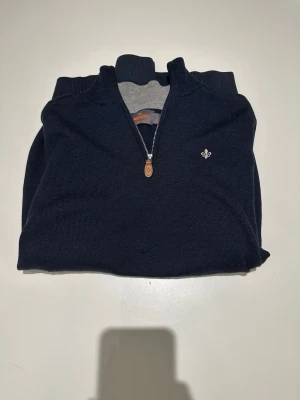 Morris halvzip - Snygg mörkblå stickad tröja från Morris i 100% merinoull. Tröjan har halv dragkedja, ståkrage och en liten broderad logga på bröstet. Perfekt för dig som gillar klassisk och stilren design. Tröjan har några deffekter(se bild 4och 5). Modellen är 187 och väger 70kg, tröjan sitter lite litet på mig. Vid frågor är det bara att skriva