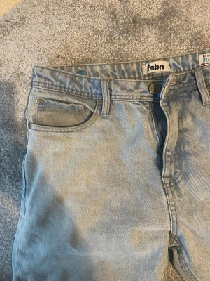 Ljusblå raka jeans från fsbn - Säljer ett par ljusblå jeans från fsbn med klassisk femficksmodell och raka ben. Jeansen har bälteshällor, knappgylf och är gjorda i ett mjukt denimtyg. Perfekta för en avslappnad och trendig look.