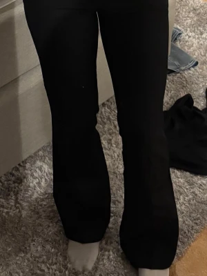 Svarta utsvängda kostymbyxor BikBok - Säljer ett par svarta kostymbyxor från Bik Bok i storlek 34. Byxorna har en klassisk rak passform med lätt utsvängda ben och hög midja. Knappen är dock borta på insidan men haken är kvar att stänga med