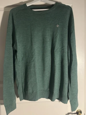 Grön rundhalsad tröja från Morris - Mysig grön tröja med rund halsringning och diskret broderad Morris logga. Långärmad modell i mjukt stickat material, perfekt för lager på lager. Ribbstickade muddar vid ärmslut och nederkant ger en snygg passform, tröjan sitter slimad på kroppen