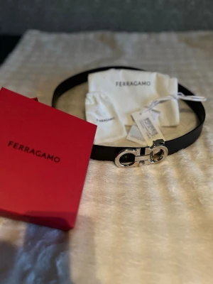 Svart Ferragamo bälte - Stilrent svart och brunt bälte från Ferragamo.äkta skin har haft den i over 1 år nu vill bli av med det serious köpare budar. Ny pris kostar över 5000 kvitto fins 