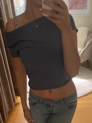 Blå/grå croppad topp från Gina Tricot - Enkel och stilren blå/grå croppad topp från Gina Tricot. Toppen har korta ärmar, rundad halsringning och är gjord i mjuk bomull. Perfekt att matcha med jeans eller kjol för en avslappnad look.