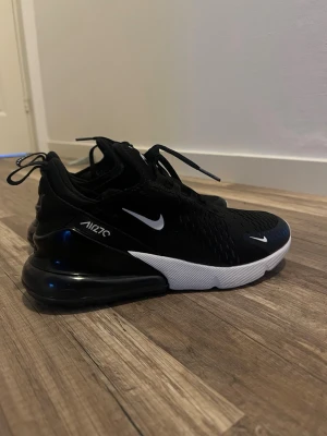 Nike Air Max 270 svarta sneakers - (Pris går att diskuteras!) Snygga svarta Nike Air Max 270 sneakers med vit sula och tydlig Air Max-dämpning i hälen. Ovandelen är i mesh för bra ventilation och har vita detaljer som swoosh-loggan och texten 'AIR270'. Perfekta för en sportig och trendig look.
