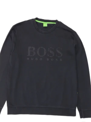 Svart sweatshirt från Hugo Boss - Stilren svart sweatshirt från Hugo Boss med rund halsringning och stort BOSS-tryck på bröstet. Tröjan har långa ärmar och ribbade muddar vid ärmslut och nederkant. Perfekt för en avslappnad och trendig look.