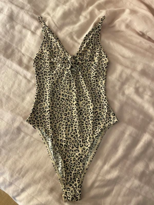 Leopardmönstrad body - Snygg body från Bik Bok med leopardmönster i beige och svart. Djup urringning fram och smala axelband. Materialet är stretchigt och följsamt. Trendig och djärv look som sticker ut.