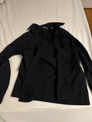 Svart skjorta från Jack & Jones - Stilren svart overshirt från Jack & Jones med klassisk krage och bröstfickor. Overshirten har knappar framtill och är långärmad. Perfekt för dig som gillar en enkel men snygg look.