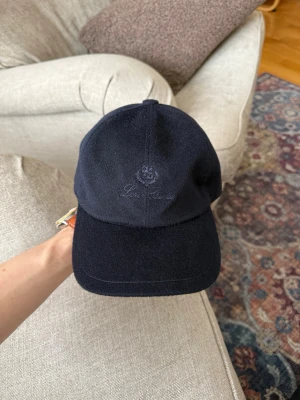 Loro piana Kashmir keps  - Snygg mörkblå keps från loro piana med broderad logga och text framtill. Klassisk böjd skärm och justerbar baksida. Tillverkad i ett mjukt tyg som ger en stilren och avslappnad look.