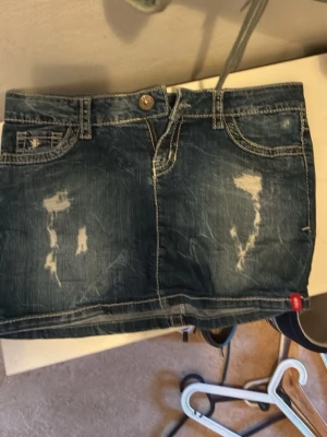 Blå jeanskjol från DC loves Esprit - Säljer en blå jeanskjol från DC loves Esprit med slitna detaljer och klassisk femficksdesign. Kjolen är kort och har tydliga kontrastsömmar samt knapp och dragkedja framtill. Perfekt för dig som gillar en avslappnad och trendig stil.