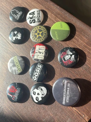 Band-och musik pins - Säljer ett gäng gamla pins som jag inte använder längre, 5st med misfits motiv (band), 4st med attentat motiv (band) 1 oasis (band) 1 The walking dead (serie) 1 "ska" av the specials (band) 120kr totalt, 10kr styck, pris kan diskuteras 🫶🏻   (Alla fungerar som vanligt med nål på baksidan)