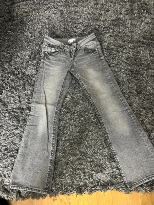 Grå bootcut jeans med slitningar sop - S sop gråa bootcut jeans med snygga slitningar och klassisk femficksdesign. Jeansen har en lätt tvättad look och raka ben som går ut något nedtill. Perfekta för en avslappnad och trendig stil.