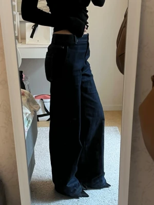 Mörkblåa vida jeans - Säljer ett par marinblåa jeans från Zara i storlek 26. De är vida jeans med midwaist. Mycket gott skick och använda fåtal gånger. Små defekter längst ned vid fötterna!🩷