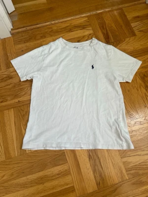 Vit t-shirt från Polo Ralph Lauren - Säljer en  vit t-shirt från Polo Ralph Lauren med korta ärmar och rund hals💕💕. T-shirten har den ikoniska mörkblå loggan broderad på bröstet💕I mycket bra skick💕💕Jag säljer den för 100 kr💕💕Hör av er vid intresse💕💕