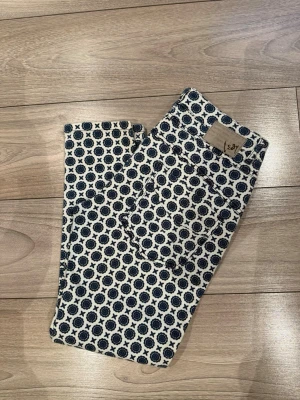 Mönstrade jeans från Isay - Säljer ett par unika jeans från Isay med blått cirkelmönster på vit botten. Modellen är slim fit med normal midja och klassiska fem fickor. Materialet är mjukt och stretchigt för extra komfort. Perfekta för dig som vill sticka ut med din stil!