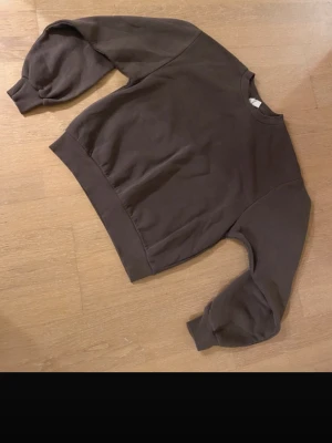 Lila sweatshirt utan huva - En enkel brun sweatshirt med rund hals och breda muddar vid ärmar och nederkant. Tröjan har en avslappnad passform och är tillverkad i mjukt bomullsmaterial. Perfekt för en chill och casual stil. Den är från Gina Tricot 