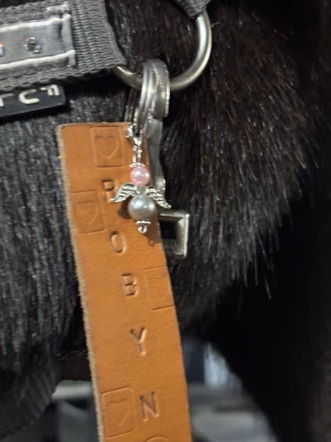 Söt ängelberlock med pärlor - En liten berlock formad som en ängel med silverfärgade vingar och två pärlor, en rosa och en vit. Perfekt att hänga på nyckelring, väska eller som dekoration på smycken. Ger en gullig och personlig touch till din stil.