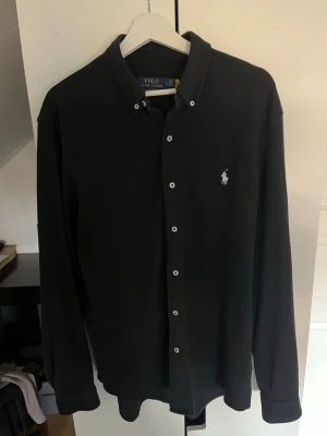 Svart skjorta från Polo Ralph Lauren - Otroligt snygg skjorta från Ralph Lauren i storlek L. Riktigt bra skick. Skicka gärna prisförslag. Kika in min profil för mer schyssta plagg