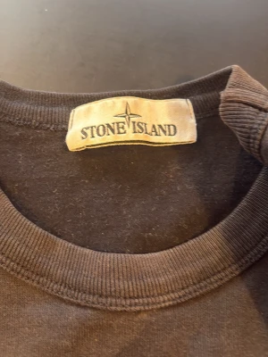 Svart sweatshirt från Stone Island - En stilren svart sweatshirt från Stone Island med klassisk rund halsringning och ribbade muddar. Tröjan har den ikoniska Stone Island-loggan på vänster ärm och är tillverkad i mjuk bomull för maximal komfort. Köpte för 2500