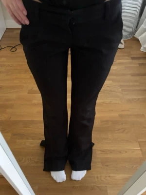 Svarta kostymbyxor med bootcut - Säljer ett par svarta kostymbyxor med bootcut och klassisk passform. Byxorna har fickor fram och stängs med knapp och dragkedja. Perfekta för dig som vill ha en stilren look. Innerbens längd är 79/80cm 