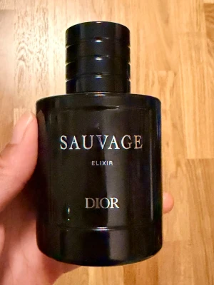 Dior Sauvage Elixir 100 ml parfym - Dior Sauvage Elixir är en exklusiv parfym i en mörkblå, stilren glasflaska med silverdetaljer. Doften är intensiv och maskulin, perfekt för dig som vill sticka ut. Flaskan har en rund form och känns lyxig i handen. Köpt till pojkvän men han använder inte. Helt ny, har i princip endast luktat på den.  Köpt för 2700kr, på DIORs hemsida går den på 2820kr.  Kvittot är bortslarvat