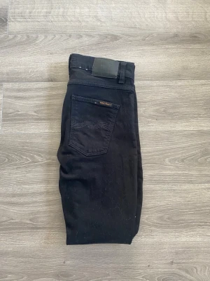 Nudie Jeans - Ett par svarta nudie jeans. Sparsamt använda och inga fläckar/defekter. De har legat i garderoben ett tag och som ni vet så samlar svart på sig en del damm. Det går dock att rolla bort så ingen fara✅ Storlek 31:32 på jeansen i modellen Lean Dean. Ett par överlag schyssta jeans som är enkla att matcha. Obs❗️Första bilden med mått är 102cm👍 Hör gärna av dig🙌