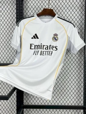 Real Madrid matchtröja Adidas - Säljer en vit Real Madrid matchtröja från Adidas med svarta detaljer och gula linjer. Tröjan har klubbens emblem på bröstet och sponsorloggan 'Emirates Fly Better' tryckt framtill. Perfekt för fotbollsfans som vill representera sitt lag.