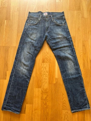 Edwin ED-80 Slim Tapered Jeans – W30 L32 - Säljer ett par riktigt schyssta jeans från japanska Edwin i deras populära modell ED-80 (Slim Tapered). Modellen har en modern, slimmad passform med ben som smalnar av snyggt nedåt. En perfekt allround-jeans i en klassisk mörkblå tvätt som passar till allt. Märke: Edwin Modell: ED-80 Slim Tapered Storlek: W30 / L32 Detaljer: Klassisk läderpatch baktill, signatur-broderier på bakfickorna och knappgylf. Skick: Bra skick och använda väl så de ser vintage ut.