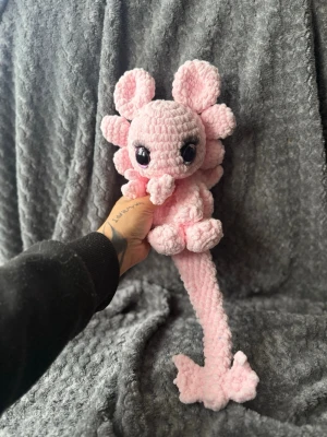 Rosa virkad drake - Supersöt handvirkad drake med stora svarta ögon och långa ögonfransar. Draken har gulliga öron, små vingar och en lång svans. Perfekt som dekoration eller present till någon som gillar söta saker.