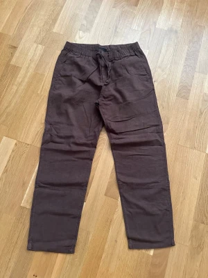 Bruna linen från H&M - Mörkbruna linen från H&M med avslappnad passform och resår i midjan samt dragsko. 