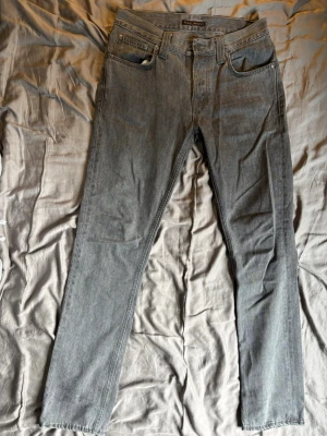 Gråa Nudie Jeans. - Säljer ett par gråa jeans från Nudie Jeans i storlek w31 och l34. Midjan har en bredd på 40cm, längd på 110cm och lårbredd på 52cm. Priet kan diskuteras. Vet ej modellen på jeansen.