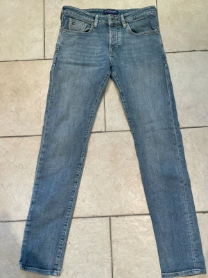 Ljusblå jeans Scotch & Soda - Säljer ett par ljusblå  jeans från Scotch & Soda. Klassisk femficksmodell med dragkedjegylf och läderpatch bak i midjan. Jeansen har en smal passform och är tillverkade i mjuk denim med lätt tvättad look. Storlek W29 L34