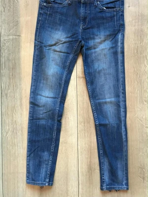 Jeans från Lindex Skinny cropped strl 28 S - Snygga blå skinny jeans med dragkedjor vid bensluten och klassiska fickor både fram och bak.   Hela och rena