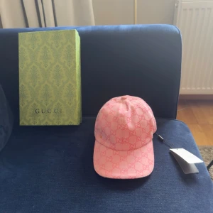 Rosa keps från Gucci med GG-mönster - Snygg rosa keps från Gucci med det klassiska GG-monogrammet i hela tyget. Kepsen har böjd skärm och justerbar rem bak. Tillverkad i ett slitstarkt tyg som känns lyxigt och trendigt. Perfekt accessoar för att lyfta din outfit.