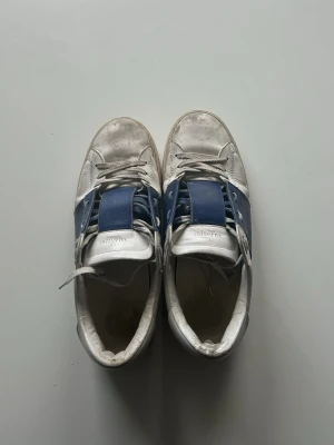 Valentino vita och blå sneakers - Jag säljer mina vita Valentino skor då jag inte har nån användning av dom längre. Dom är i bra skick ( lite slitna på framsidan av skorn ) jag diskuterar gärna pris då jag inte vet vad jag tar för dom