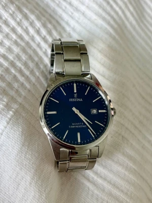 Herr armbandsklocka-FESTINA - F20511/3 - Stilren herrklocka från Festina med blå urtavla.  Armbandet är i silverfärgad metall och vattentålig upp till 5 bar. Perfekt accessoar för dig som gillar enkel och tidlös design. Finns lite repor på armbandet se sista bild. 