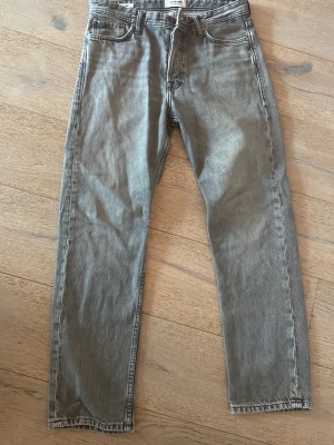 Grå raka jeans från Jack & Jones - Säljer ett par grå jeans från Jack & Jones med rak passform och klassisk femficksdesign. Jeansen har knappgylf och är tillverkade i denim med snygg tvättad look. Perfekta för en avslappnad stil. Modell loose chris 29/30