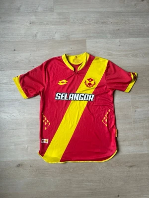 Röd Selangor FC Fotbollströja 2017 Storlek M - Mycket fin fotbollströja i röd färg. Tröjan är i mycket bra skick och sparsamt använda. |  Äkta som allt annat jag säljer! ✅ |  Storlek: M | Skick: Mycket Bra Skick -  (SE SISTA BILD)| Färg: Röd | Märke: Lotto | Modell: Fotbollströja |   Hör gärna av dig vid frågor så svarar jag så fort jag kan! 😁