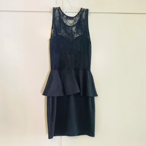 Klänning  - Snygg svart kortklänning med peplum volang 