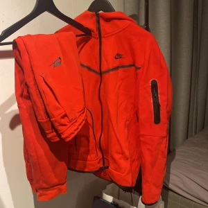 Nike Thech Fleece/Röd - Köp min unika röda tracksuit, Tröjan är i storlek Large och byxorna är i storlek Medium. 500kr och tracksuiten är din, Säljer tyvär inte separat.