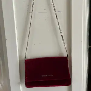 Helt oanvänd Karen Millen handväska i burgundy röd. Går att förlänga och korta ner bandet beroende på hur du föredrar att använda den!