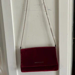 Karen Millen handväska  - Helt oanvänd Karen Millen handväska i burgundy röd. Går att förlänga och korta ner bandet beroende på hur du föredrar att använda den!