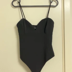 Svart bodysuit - Svart bodysuit med knappar i storlek S, helt oanvänd